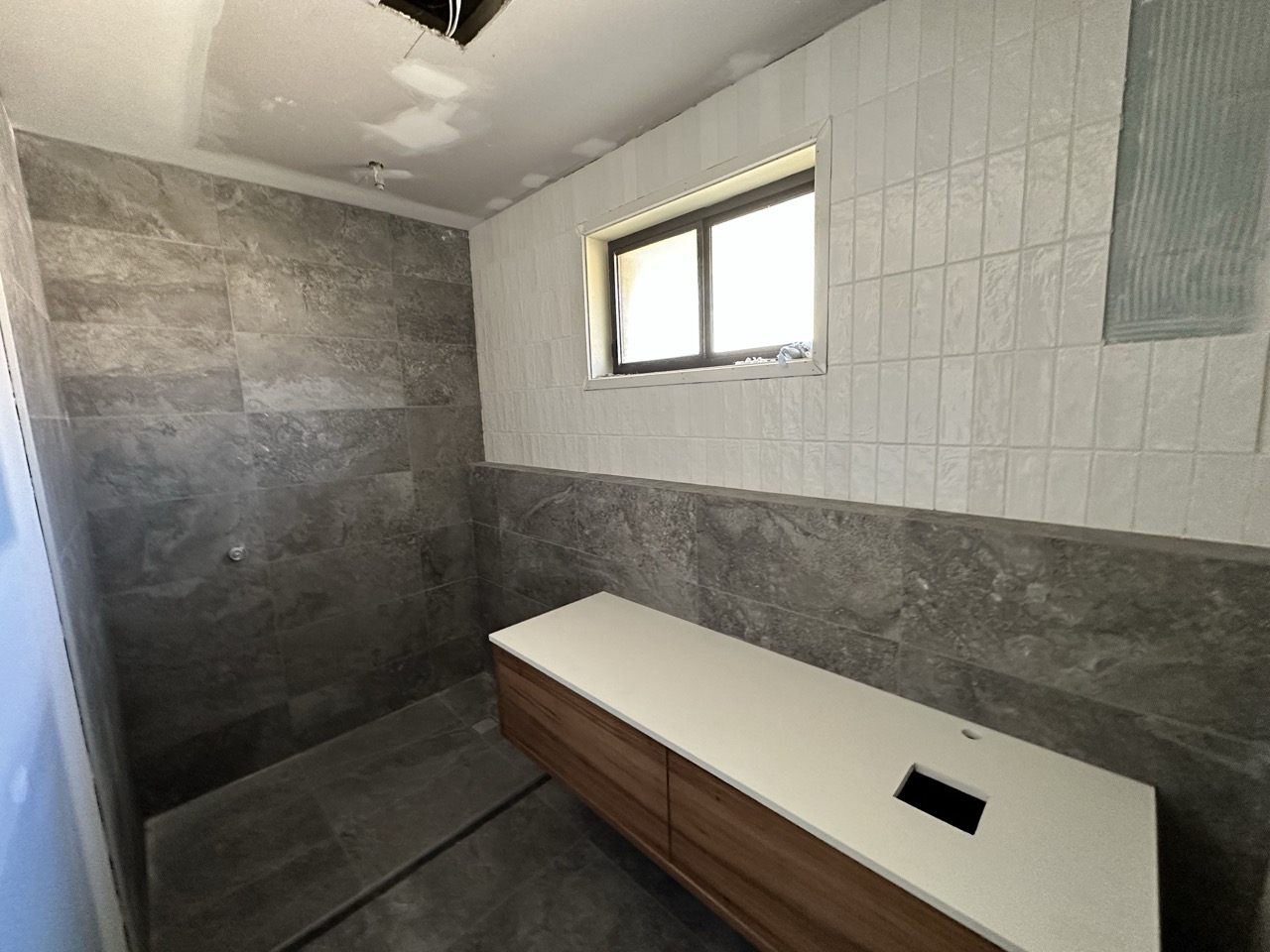 Bathroom renovation with tiled walls and timber vanity